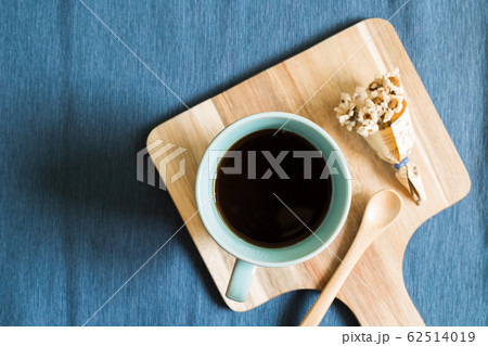 Coffee, spoon and flower on wooden tray on blue cloth background 62514019