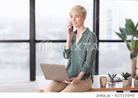 Entrepreneur Woman Talking On Cellphone Sitting On Desk In Office 62515040