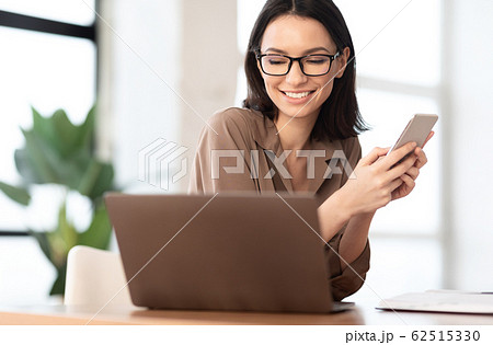 Portrait of busy girl using cellphone and computer 62515330
