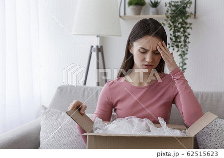 Upset woman customer unpacking delivered cardboard parcel Upset woman customer unpacking delivered cardboard parcel 62515623