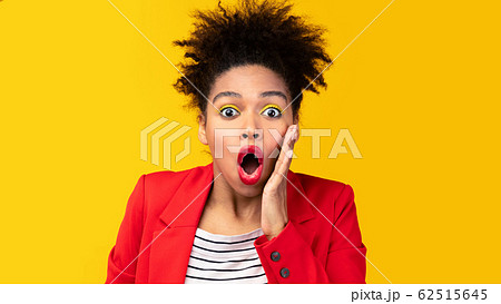 Surprised afro woman screaming and touching her cheek 62515645