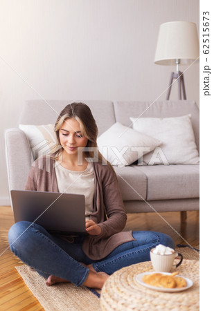 Millennial girl typing on laptop, studying on floor at home Millennial girl typing on laptop, studying on floor at home 62515673