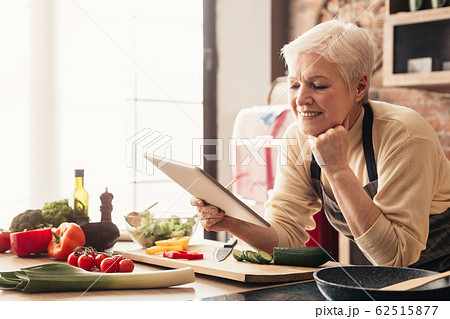 Elderly woman using digital tablet in kitchen, checking cooking recipes Elderly woman using digital tablet in kitchen, checking cooking recipes 62515877