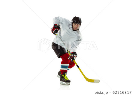 Young male hockey player with the stick on ice court and white background 62516317