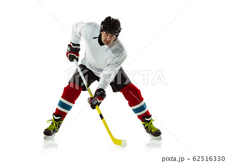Young male hockey player with the stick on ice court and white background Young male hockey player with the stick on ice court and white background 62516330