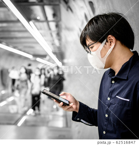 Asian man wearing mask using phone in subway Asian man wearing mask using phone in subway 62516847