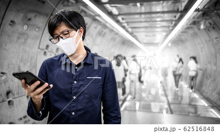 Asian man wearing mask using phone in subway 62516848