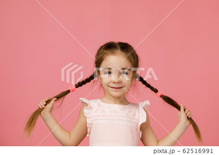 Cute small child girl holding long hair braids Cute small child girl holding long hair braids 62516991