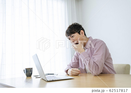 ノートパソコンの前で驚く男性 62517817