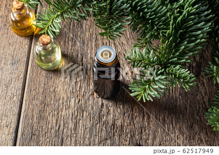 A dropper bottle of essential oil with fresh fir branches 62517949