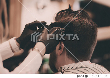 Barber in black gloves cuts a man's hair Barber in black gloves cuts a man's hair 62518226
