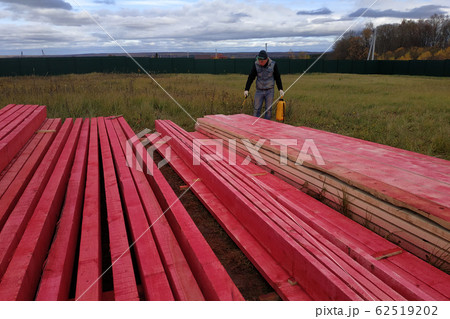 Worker covers wooden boards with protective paint. 62519202