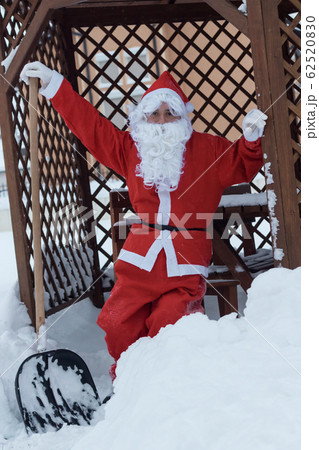 Proud santa claus lean on shovel after work of Proud santa claus lean on shovel after work of 62520830