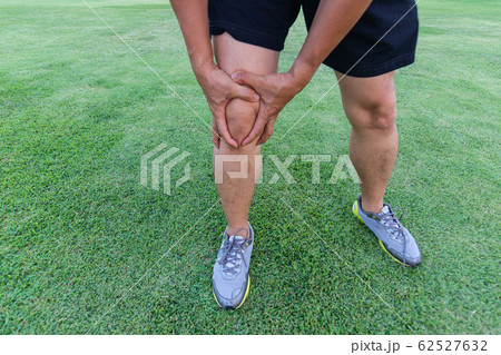 man hold Tendon knee joint problems on Man leg from exercise In the stadium.   62527632