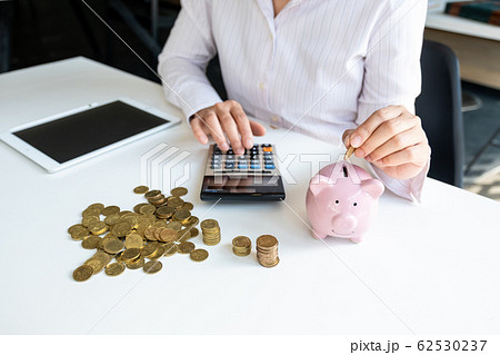 Pink piggy bank with business woman in office, saving for new business target and retirement concept Pink piggy bank with business woman in office, saving for new business target and retirement concept 62530237