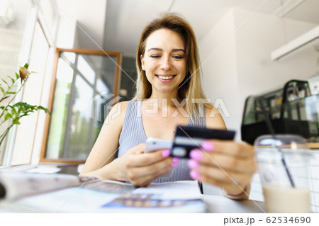 Focus on happy girl using smartphone and debit card for booking tickets. 62534690