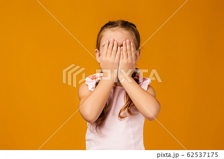 Cute little child girl closes her eyes with her hand Cute little child girl closes her eyes with her hand 62537175