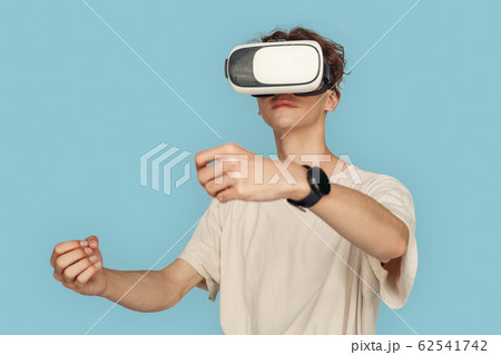 Freestyle. Man in vr headset standing isolated on gray playing game driving concentrated 62541742