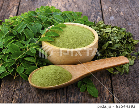 Moringa powder in wooden bowl with fresh Moringa Moringa powder in wooden bowl with fresh Moringa 62544392