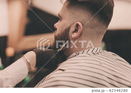 Barber cuts the beard of man 62546280