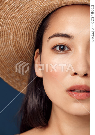 Freestyle. Young woman in hat standing isolated on dark blue half face close-up looking camera curious Freestyle. Young woman in hat standing isolated on dark blue half face close-up looking camera curious 62549013