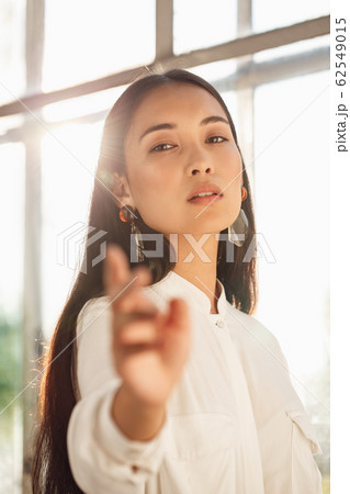 Freestyle. Young woman standing near window hand towards camera sensual close-up 62549015