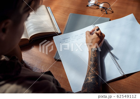 Exam Preparation. Young woman sitting taking notes back view close-up 62549112