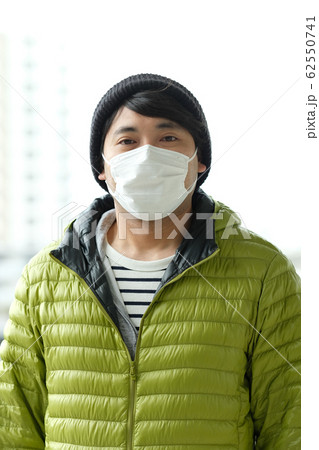 屋外で感染症予防の為に衛生マスクをしているニット帽をかぶった日本人男性のウエストアップ正面 62550741