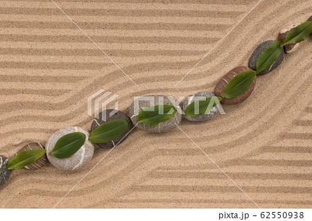 Leaves lie on stones on zigzag lines of sand. Leaves lie on stones on zigzag lines of sand. 62550938