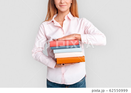 Freestyle. Young woman student standing isolated on white with books close-up smiling confident Freestyle. Young woman student standing isolated on white with books close-up smiling confident 62550999