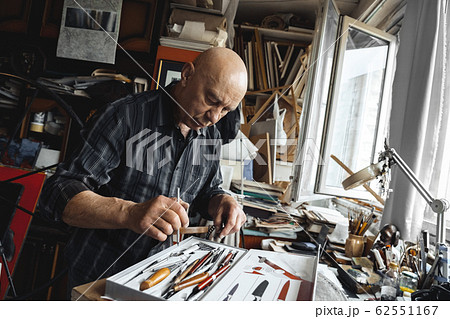 Man working at typograhpy studio indoors choosing tool pensive Man working at typograhpy studio indoors choosing tool pensive 62551167