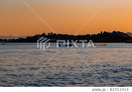 Sunset, lake sparkling. Fishermen driving a small fishing boat in fishing. Sunset, lake sparkling. Fishermen driving a small fishing boat in fishing. 62551413