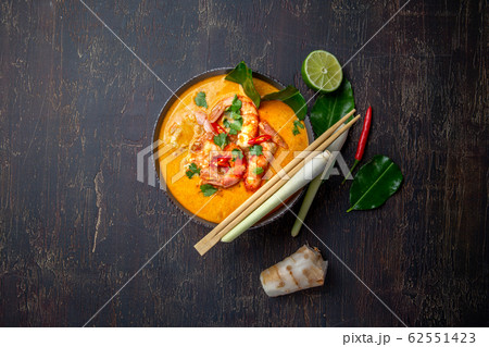 Shrimps Tom Yam Kung in grey bowl with thai spices on autentic tray top view, wooden background. 62551423
