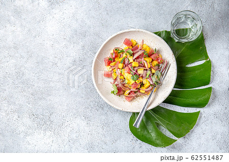 Tropical Hawaiian tahitian tuna mango salad on white plate on tropical monstera leafe Tropical Hawaiian tahitian tuna mango salad on white plate on tropical monstera leafe 62551487