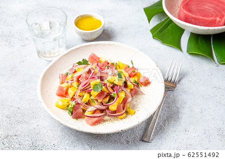 Tropical Hawaiian tahitian tuna mango salad on white plate on tropical monstera leafe Tropical Hawaiian tahitian tuna mango salad on white plate on tropical monstera leafe 62551492