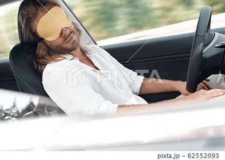 Tired man sitting in car, wearing in sleeping mask 62552093