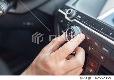 Transportation. Young man traveling by electric car sitting inside rolling control button changing temperature close-up Transportation. Young man traveling by electric car sitting inside rolling control button changing temperature close-up 62552359