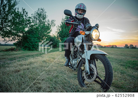 young attractive woman on motorcycle on dirt road at sunset 62552908