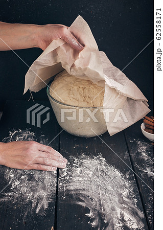 Female hands hold a napkin over a fermented homemade pastry Female hands hold a napkin over a fermented homemade pastry 62558171