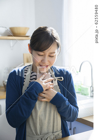 携帯を握り締めて喜ぶ若い主婦 62559480