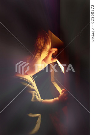 小さな子供が光を放つ物をのぞき込んでいる 小さな子供が光を放つ物をのぞき込んでいる 62560572