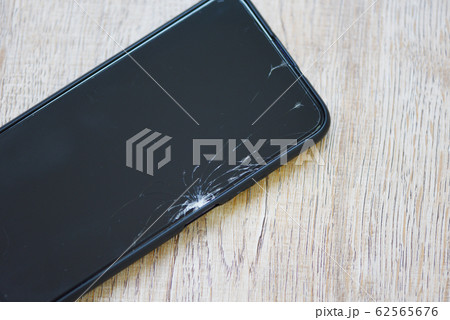 Smartphone broken glass screen on wood background Smartphone broken glass screen on wood background 62565676