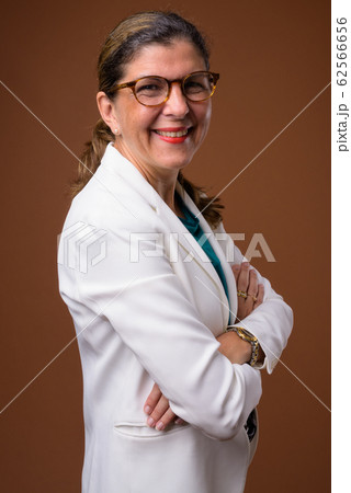 Mature beautiful businesswoman against brown background Mature beautiful businesswoman against brown background 62566656