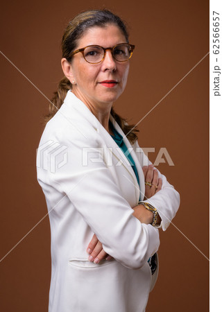 Mature beautiful businesswoman against brown background Mature beautiful businesswoman against brown background 62566657