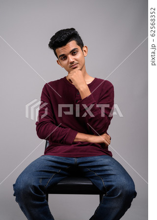 Young Indian man against gray background 62568352