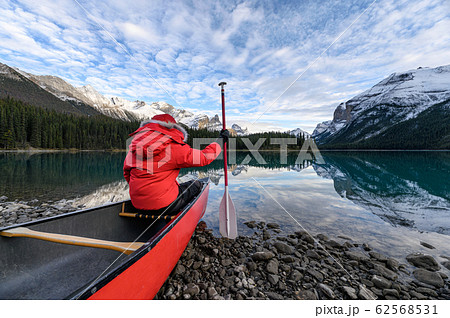Man traveler holding paddle on red canoe in Spirit Man traveler holding paddle on red canoe in Spirit 62568531