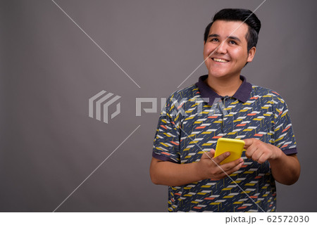 Young multi-ethnic man against gray background 62572030