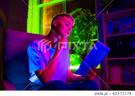 Cinematic portrait of handsome young woman in neon lighted interior 62572178
