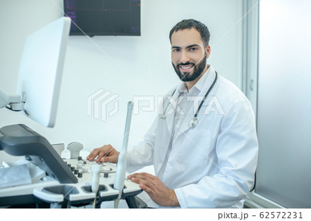 Male doctor in white robesitting at the ultrasonic device 62572231