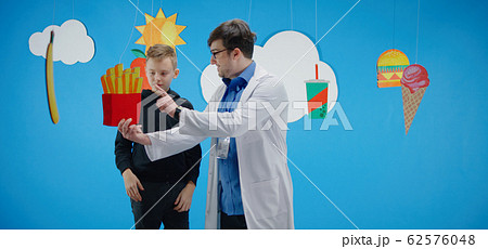 Doctor explaining to boy about healthy and unhealthy food Doctor explaining to boy about healthy and unhealthy food 62576048